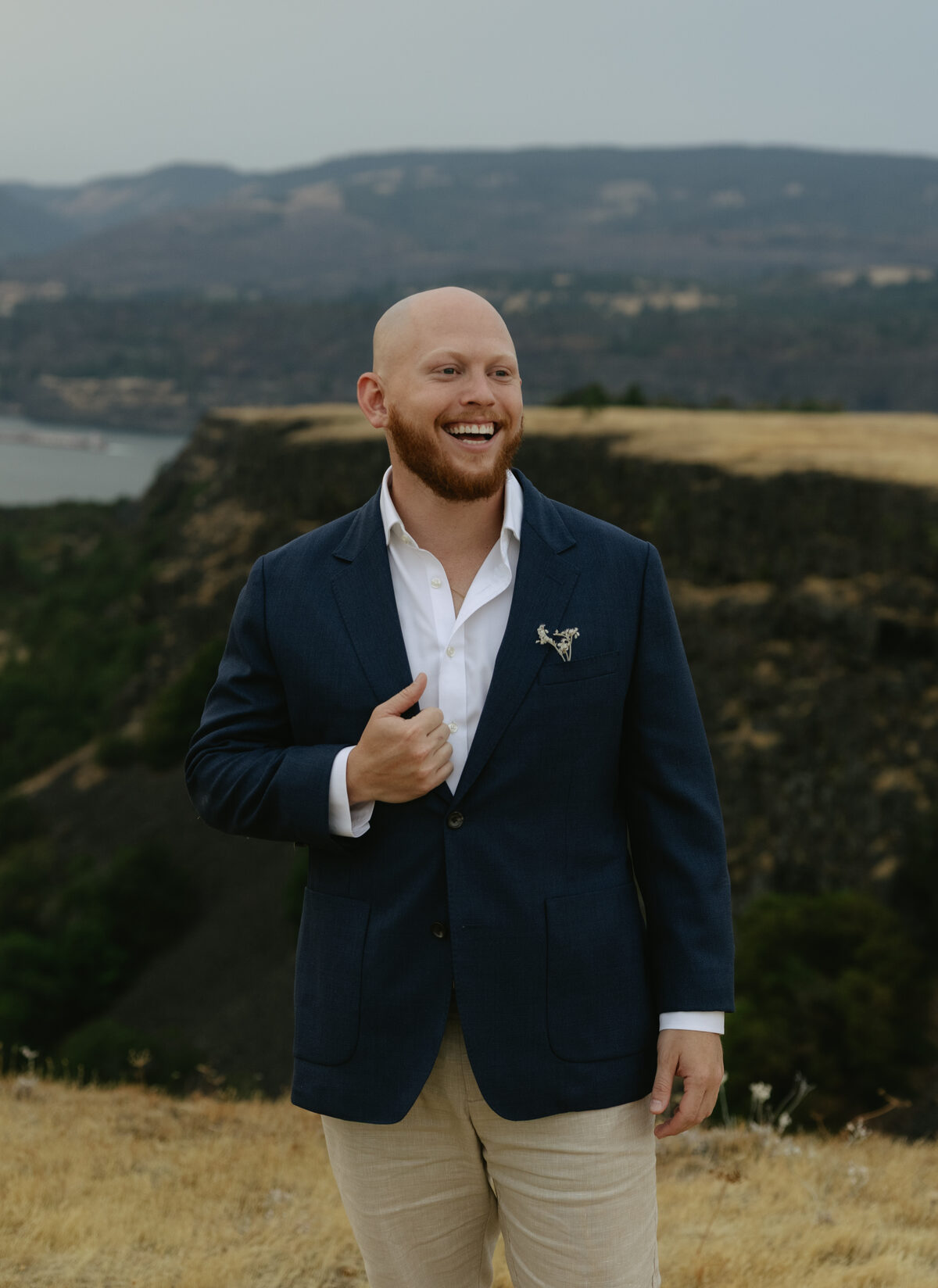 Ari Mendelow, smiling, in a navy blazer on a grassy overlook above a river gorge.